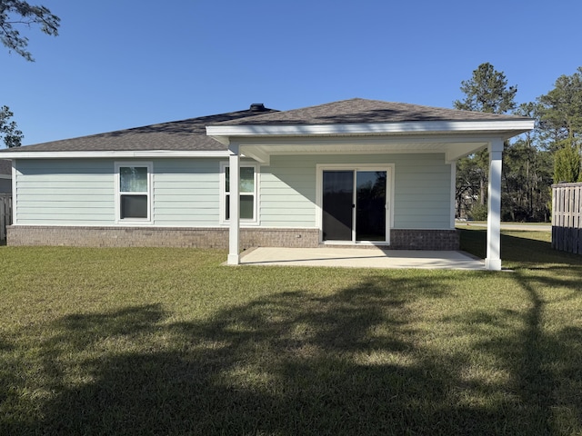 back of house with a patio, a yard, brick siding, and roof with shingles