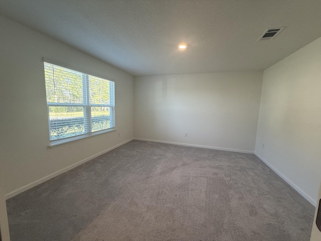 empty room with visible vents, baseboards, a textured ceiling, and carpet flooring