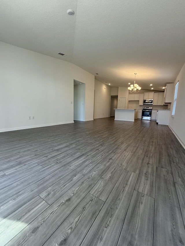 unfurnished living room featuring visible vents, dark wood-type flooring, baseboards, a chandelier, and a textured ceiling