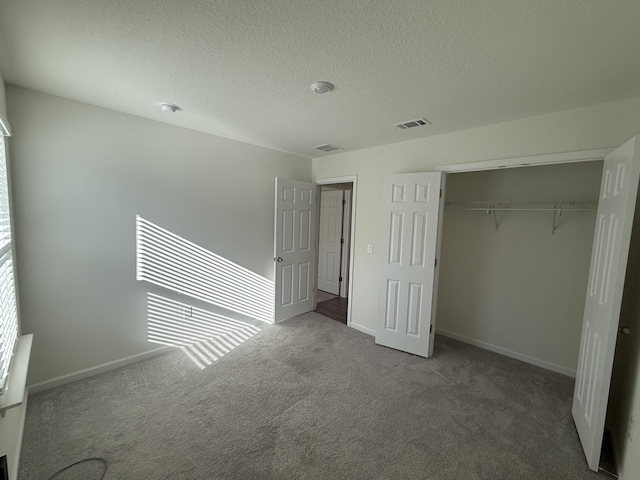 unfurnished bedroom with a closet, visible vents, carpet floors, and a textured ceiling