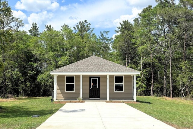 view of front facade with a shingled roof, covered porch, and a front yard