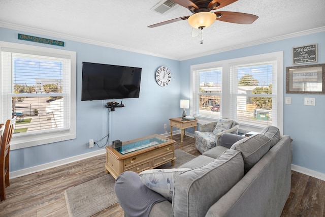 living room with ornamental molding, plenty of natural light, wood finished floors, and visible vents