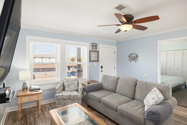 living area with a textured ceiling, visible vents, wood finished floors, and ornamental molding