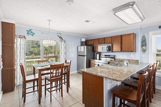 kitchen featuring crown molding, appliances with stainless steel finishes, brown cabinets, and a sink