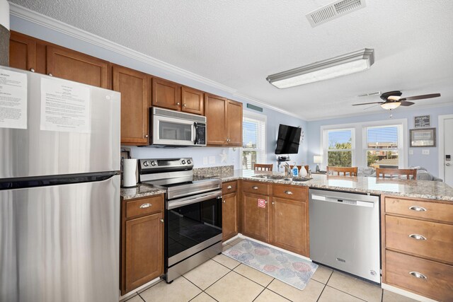 kitchen featuring stainless steel appliances, brown cabinets, visible vents, and a sink