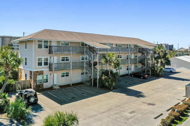 view of property featuring uncovered parking and stairway