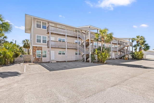 view of property with stairs and uncovered parking