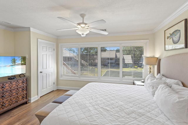 bedroom with ceiling fan, crown molding, baseboards, and wood finished floors