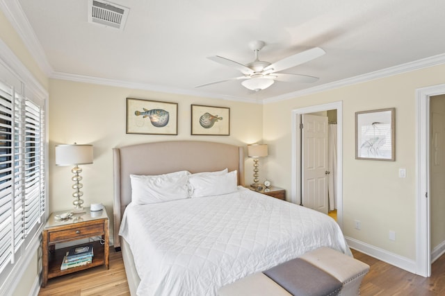 bedroom with a ceiling fan, wood finished floors, visible vents, baseboards, and crown molding