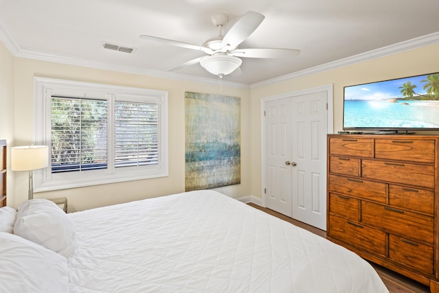 bedroom with wood finished floors, visible vents, ceiling fan, ornamental molding, and a closet