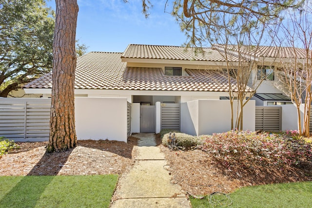 view of front facade featuring stucco siding, a tile roof, and fence