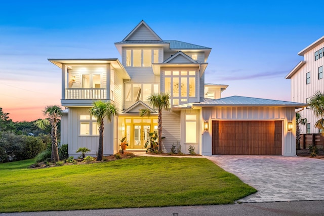 view of front facade featuring an attached garage, board and batten siding, a front yard, metal roof, and a balcony