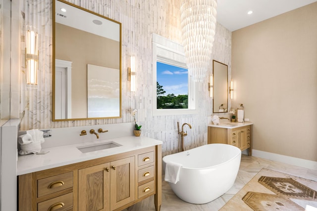 bathroom featuring a freestanding bath, baseboards, two vanities, and a sink