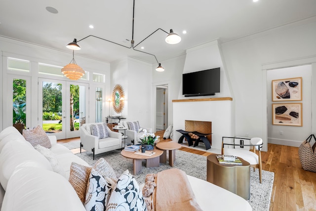 living area featuring french doors, light wood-style floors, recessed lighting, and crown molding