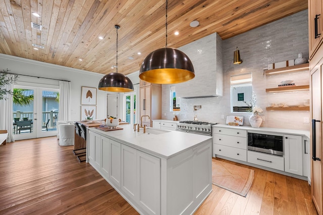 kitchen with wood ceiling, light countertops, built in microwave, tasteful backsplash, and a center island with sink