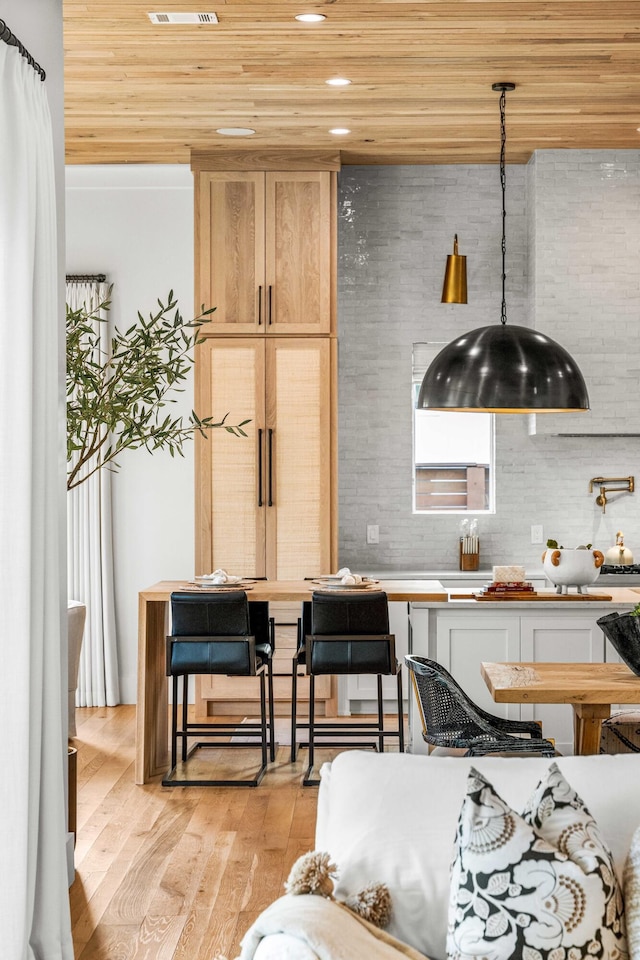 kitchen with hanging light fixtures, light wood finished floors, wooden ceiling, and recessed lighting