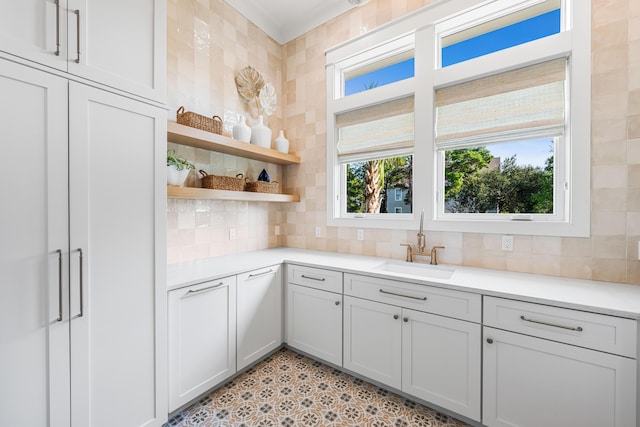 kitchen with open shelves, tasteful backsplash, light countertops, and a sink