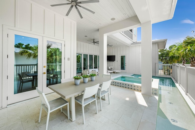 view of patio / terrace with a ceiling fan, outdoor dining space, a pool with connected hot tub, and fence