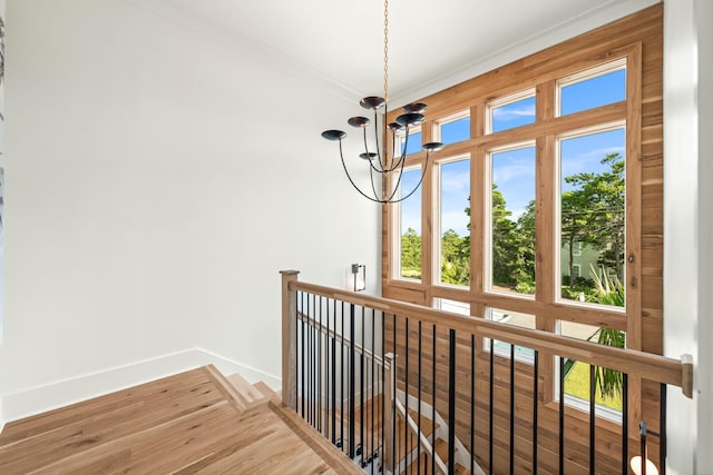 interior space with baseboards, ornamental molding, an upstairs landing, and an inviting chandelier