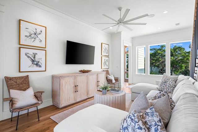 living room featuring light wood-type flooring, a ceiling fan, crown molding, and recessed lighting