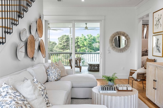 living room with ornamental molding, light wood-type flooring, visible vents, and baseboards