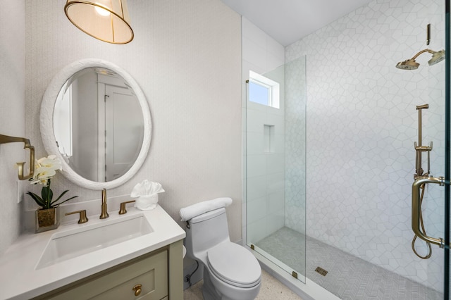 bathroom featuring vanity, a tile shower, and toilet