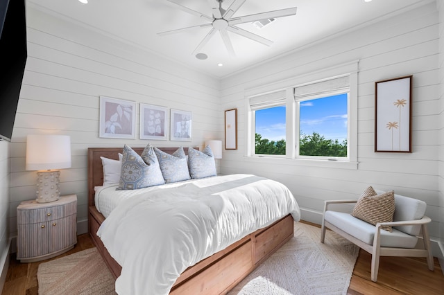 bedroom featuring a ceiling fan, baseboards, visible vents, light wood-style floors, and ornamental molding