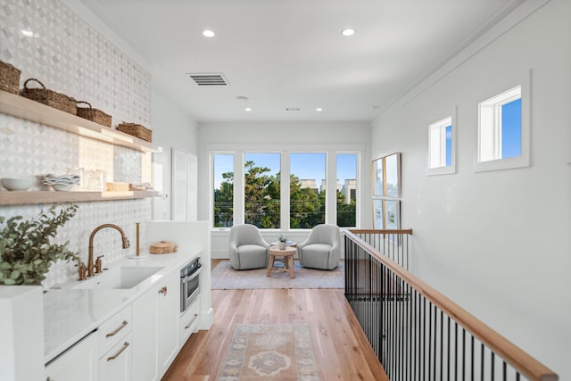 interior space with ornamental molding, light wood finished floors, visible vents, and recessed lighting