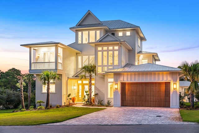 view of front of property featuring metal roof, a balcony, a lawn, decorative driveway, and board and batten siding