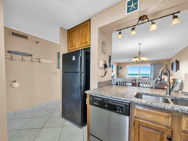 kitchen featuring visible vents, dishwasher, freestanding refrigerator, a notable chandelier, and a sink