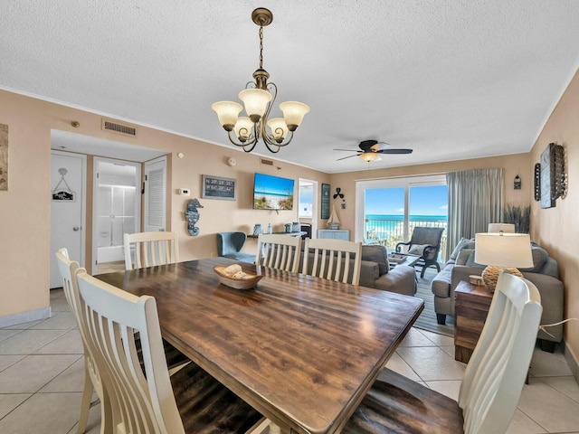 dining space with light tile patterned floors, visible vents, a textured ceiling, and ceiling fan with notable chandelier