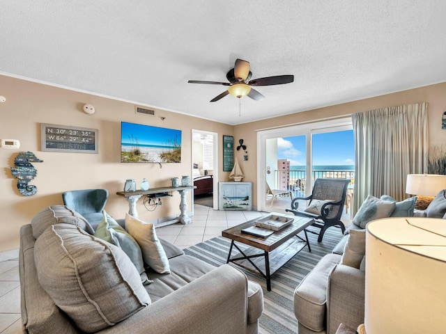 living room featuring light tile patterned floors, a textured ceiling, visible vents, and a ceiling fan