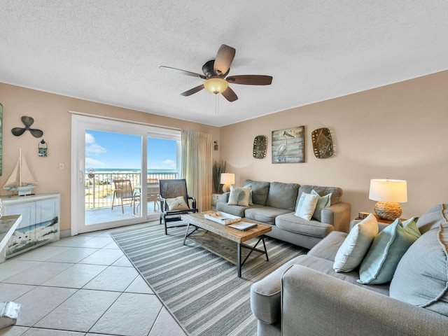 living room featuring a ceiling fan, light tile patterned flooring, and a textured ceiling