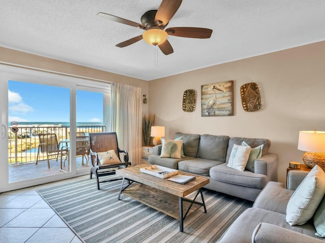 living room with light tile patterned floors, ceiling fan, and a textured ceiling