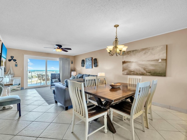 dining space with ceiling fan with notable chandelier, baseboards, a textured ceiling, and light tile patterned flooring