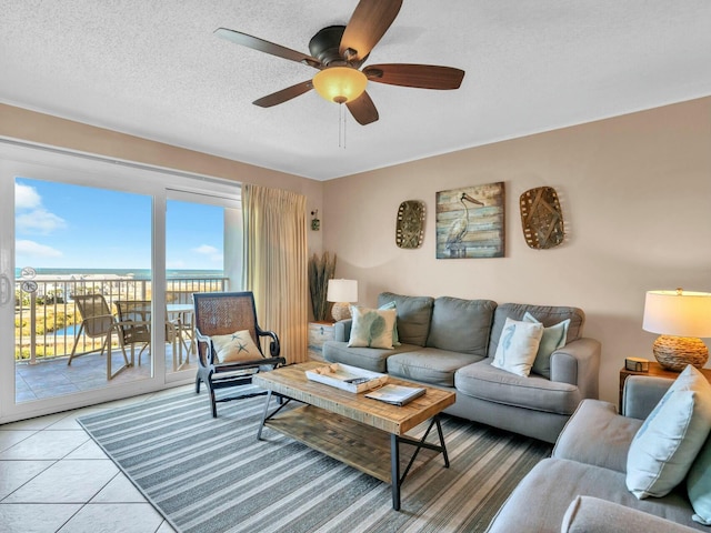 living room with light tile patterned floors, ceiling fan, and a textured ceiling