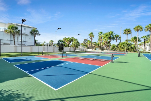 view of tennis court with community basketball court and fence