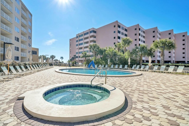 community pool with a hot tub and a patio