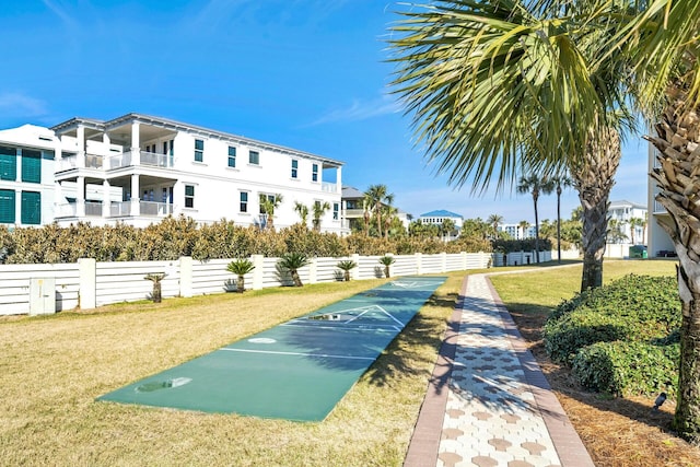 view of community featuring fence, shuffleboard, and a yard