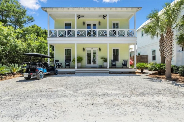 rear view of property featuring a ceiling fan, french doors, covered porch, and a balcony