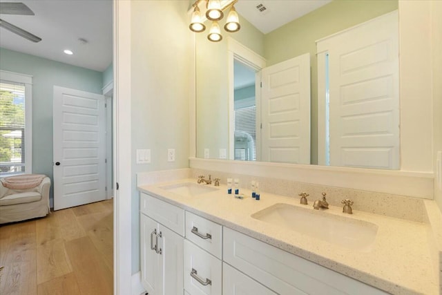 full bath featuring double vanity, wood finished floors, a sink, and visible vents