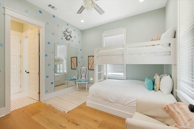 bedroom with a ceiling fan, wood finished floors, visible vents, and multiple windows