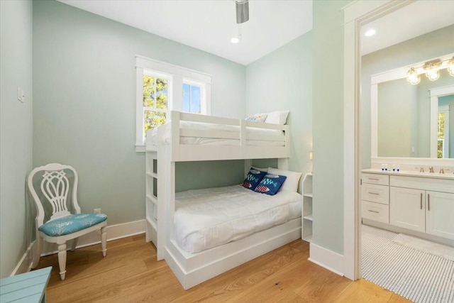 bedroom featuring ensuite bathroom, light wood finished floors, multiple windows, and baseboards