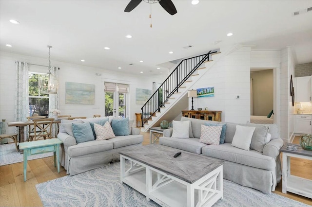 living room with recessed lighting, visible vents, stairs, light wood-type flooring, and ceiling fan with notable chandelier