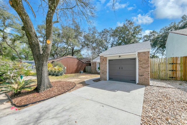 garage with concrete driveway and fence