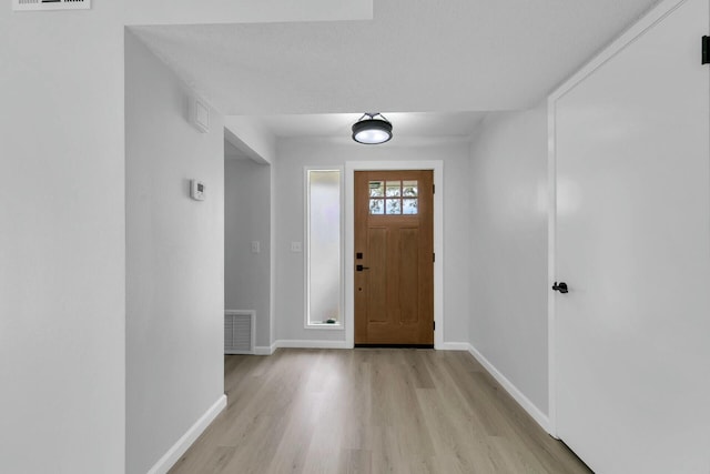 foyer featuring light wood-type flooring, visible vents, and baseboards