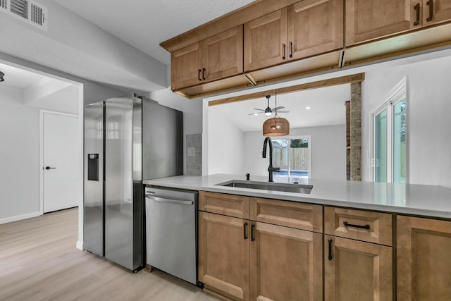 kitchen with visible vents, light wood-style flooring, a sink, stainless steel appliances, and light countertops