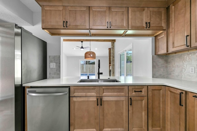 kitchen with a sink, stainless steel appliances, brown cabinetry, and light countertops