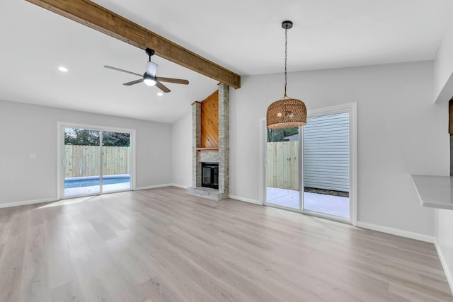 unfurnished living room with a large fireplace, light wood-type flooring, lofted ceiling with beams, and baseboards