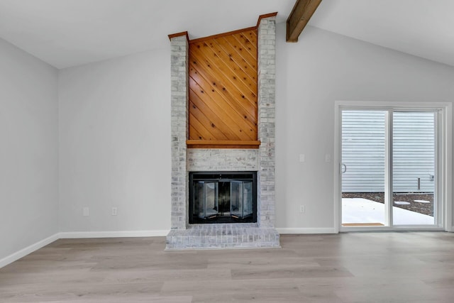 unfurnished living room featuring beam ceiling, light wood finished floors, a fireplace, and baseboards